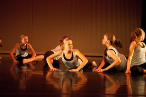 Group of teenaged dancers in a line performing floorwork in recital