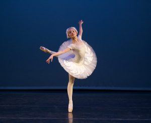 Solo dancer on pointe at Leica Hardy School of Dance performing Swan Lake variation, arms outstretched, one leg extended back.