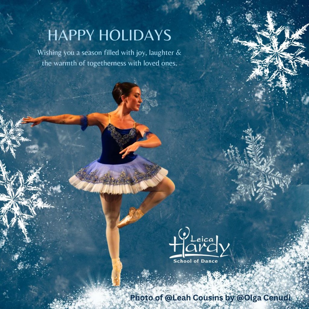 Ballet dancer in blue tutu performing on stage with snowflake background, wishing Happy Holidays from Leica Hardy School of Dance.