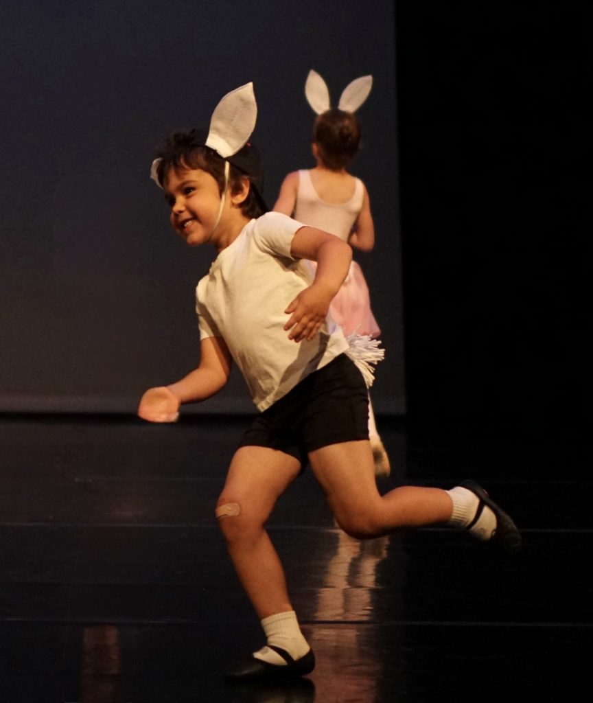 Pre-school male dance student dressed as a rabbit, skipping in recital.